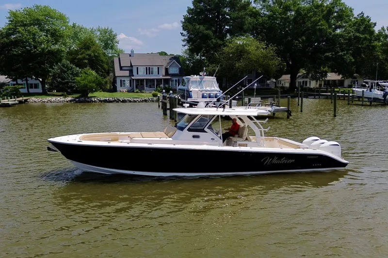 Slide: The Image of 2017 Pursuit S 408 Sport boat cruising near waterfront homes. - 16