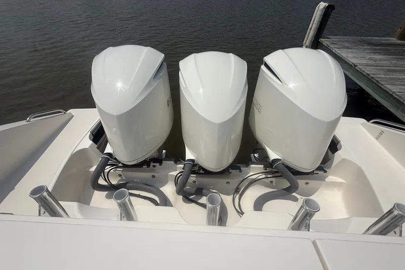 Slide: The Image of Triple outboard engines on a 2017 Pursuit S 408 Sport boat docked by the water. - 61