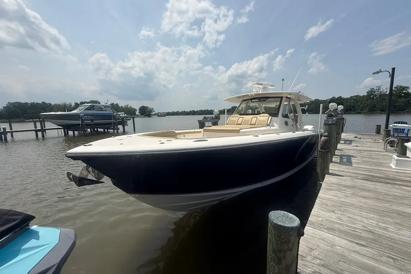 Slide: The Image of 2017 Pursuit S 408 Sport boat docked by a wooden pier under a partly cloudy sky. - 60