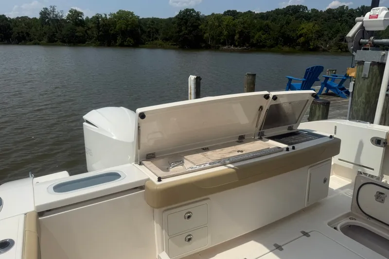Slide: The Image of 2017 Pursuit S 408 Sport boat with open storage compartments by a lakeside dock. - 20