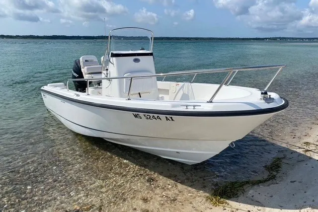 Slide: The Image of 2010 Boston Whaler 190 Outrage boat docked on a sandy shore. - 2