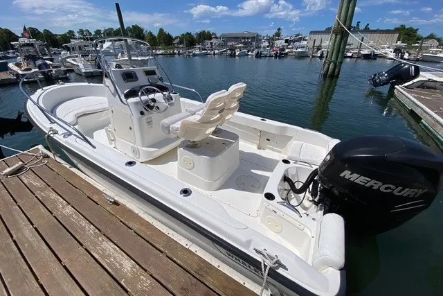 Slide: The Image of 2010 Boston Whaler 190 Outrage boat docked, featuring a Mercury outboard motor. - 6