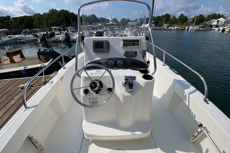 Slide: The Image of 2010 Boston Whaler 190 Outrage boat dashboard with steering wheel, docked in a marina. - 9