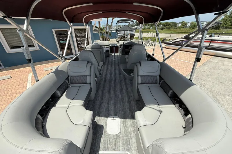 Slide: The Image of 2023 Bennington 23 LXFB pontoon boat with spacious seating and canopy, docked outdoors. - 8