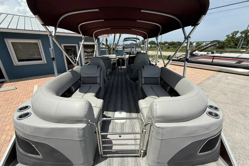 Slide: The Image of 2023 Bennington 23 LXFB pontoon boat with spacious seating and canopy, docked outdoors. - 7