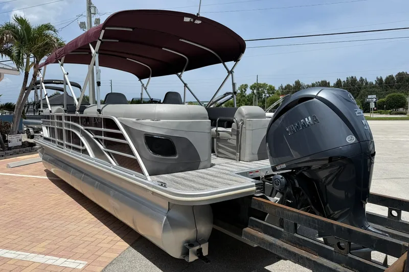 Slide: The Image of 2023 Bennington 23 LXFB pontoon boat with Yamaha engine, parked outdoors under a canopy. - 4