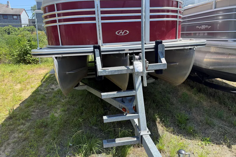 Slide: The Image of 2018 Harris Sunliner 220 pontoon boat on trailer, parked on grassy area. - 15