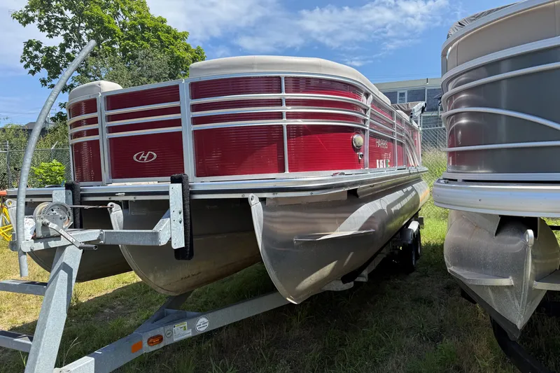 Slide: The Image of 2018 Harris Sunliner 220 pontoon boat on trailer, red exterior, parked outdoors. - 2