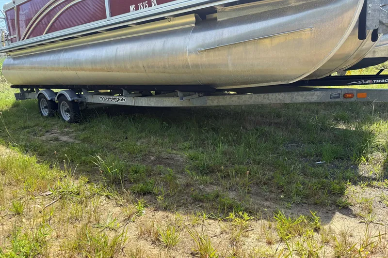 Slide: The Image of 2018 Harris Sunliner 220 pontoon boat on a trailer, parked on grassy terrain. - 16