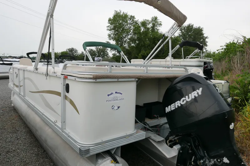 Slide: The Image of 2006 Crest 22 Super Sport pontoon boat with Mercury outboard motor, parked outdoors. - 2