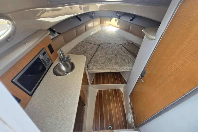 Slide: The Image of 2006 Robalo R265 Walkaround cabin interior with kitchenette, sink, and cozy sleeping area. - 1