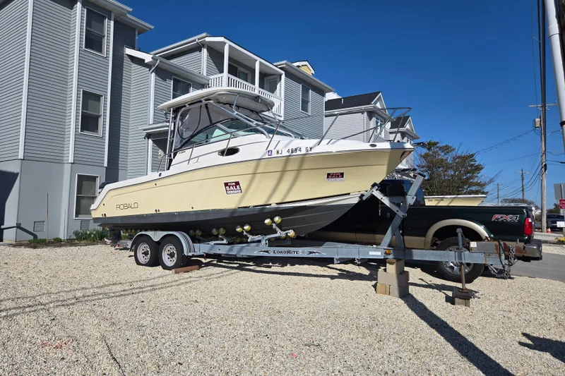 Slide: The Image of 2006 Robalo R265 Walkaround boat on trailer, parked near residential buildings, for sale. - 13