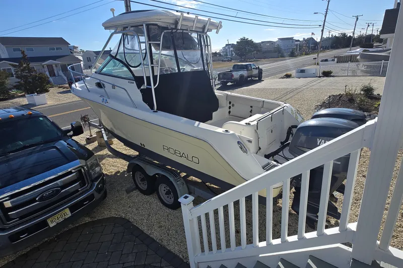 Slide: The Image of 2006 Robalo R265 Walkaround boat on trailer beside a truck in a residential area. - 7