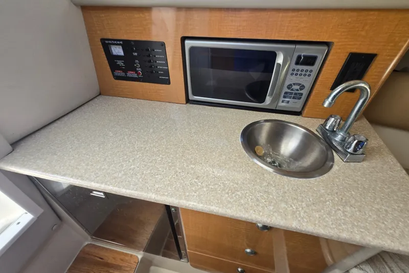 Slide: The Image of 2006 Robalo R265 Walkaround boat kitchenette with microwave, sink, and control panel. - 22