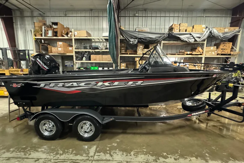 The Image of 2023 Tracker Targa V-18 WT boat in a warehouse, on a trailer, with shelves in the background. - 0