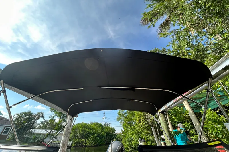 Slide: The Image of 2023 Starcraft SVX 191 OB boat with black canopy, surrounded by lush greenery. - 17