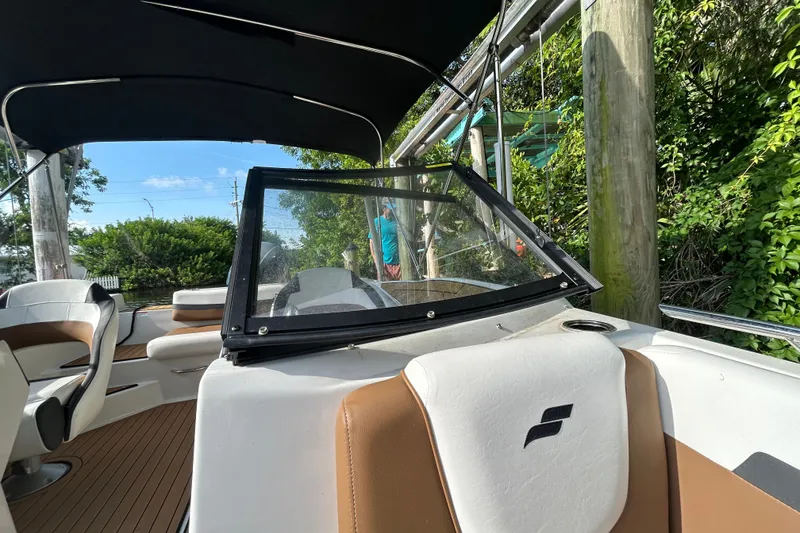 Slide: The Image of 2023 Starcraft SVX 191 OB boat interior with seating and canopy, docked near greenery. - 10
