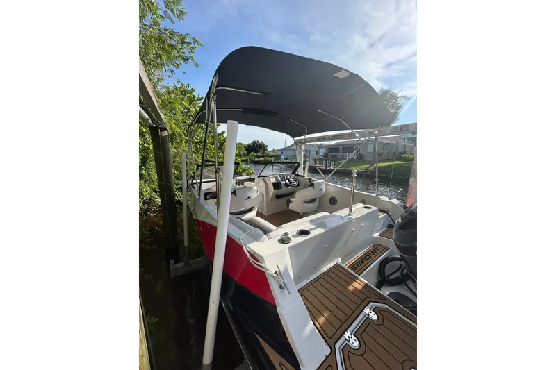 Slide: The Image of 2023 Starcraft SVX 191 OB boat docked, featuring a canopy and spacious seating. - 5