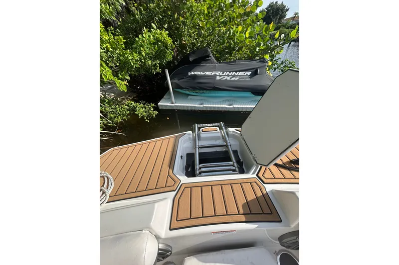 Slide: The Image of 2023 Starcraft SVX 191 OB boat with teak deck, ladder, and docked jet ski nearby. - 25