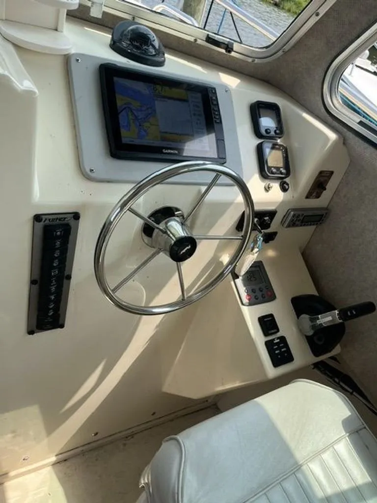 Slide: The Image of The image shows the helm of a 2011 Parker 2520 XL Sport Cabin boat. There's a steering wheel, navigation system, and various controls. - 7