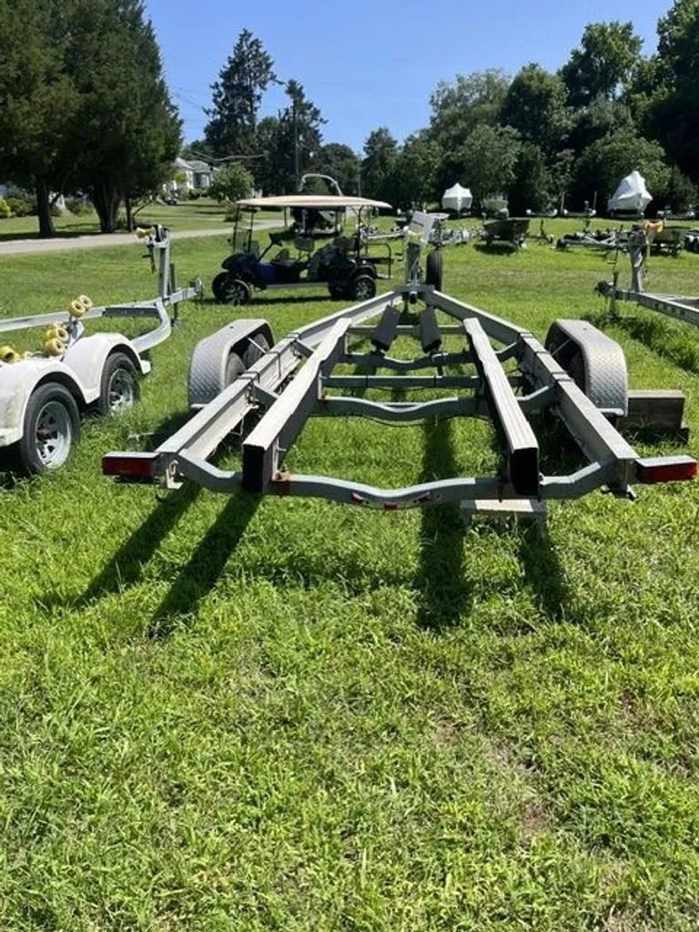 Slide: The Image of A boat trailer sits on a grassy field, surrounded by trees and other trailers. - 15