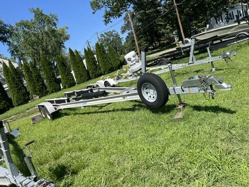 Slide: The Image of A boat trailer sits on a grassy field, surrounded by trees and other trailers. - 14