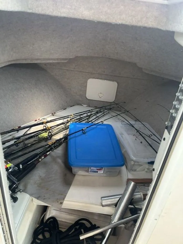 Slide: The Image of The interior of a 2011 Parker 2520 XL Sport Cabin boat features fishing rods and storage boxes. - 9