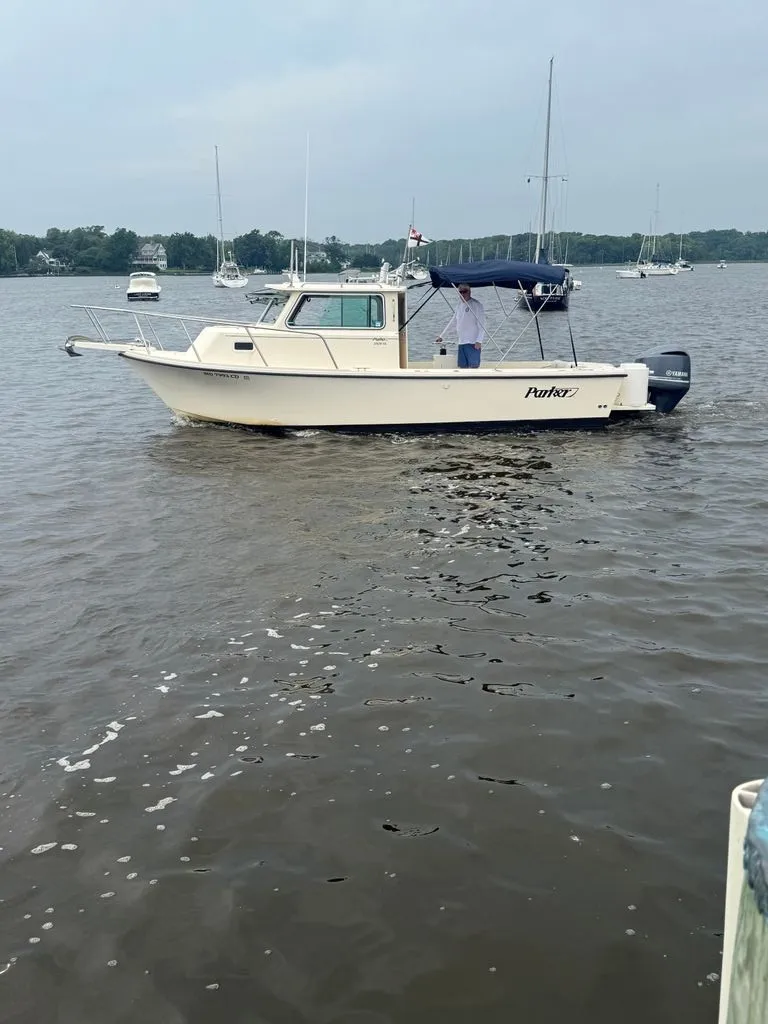 Slide: The Image of A 2011 Parker 2520 XL Sport Cabin boat on calm water. It features an enclosed cabin and a sunshade. - 1
