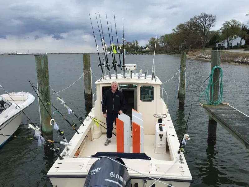 Slide: The Image of A man stands on a 2011 Parker 2520 XL Sport Cabin boat docked at a pier. - 4