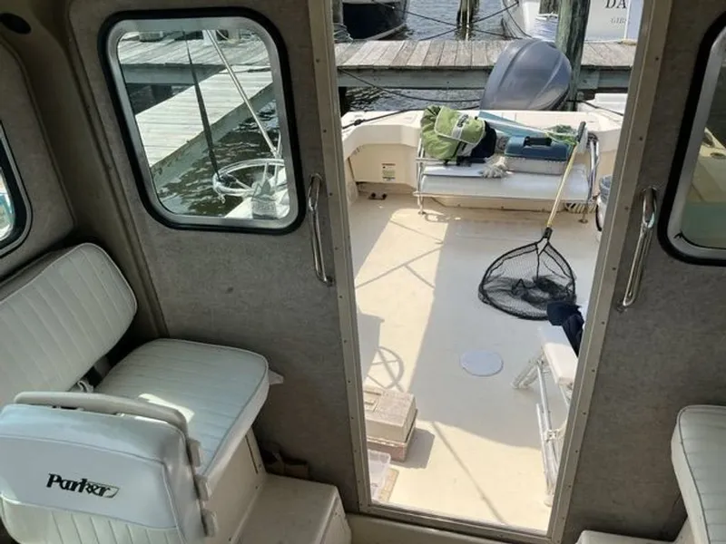 Slide: The Image of The image shows the interior of a 2011 Parker 2520 XL Sport Cabin. There are white seats and an open door leading to the deck, where fishing gear is visible. - 5