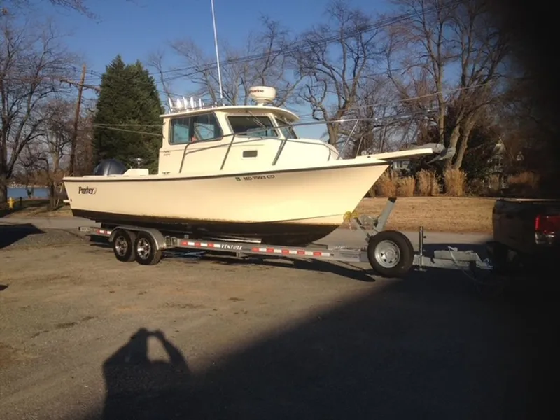 The Image of A 2011 Parker 2520 XL Sport Cabin boat on a trailer in a rural setting. - 0
