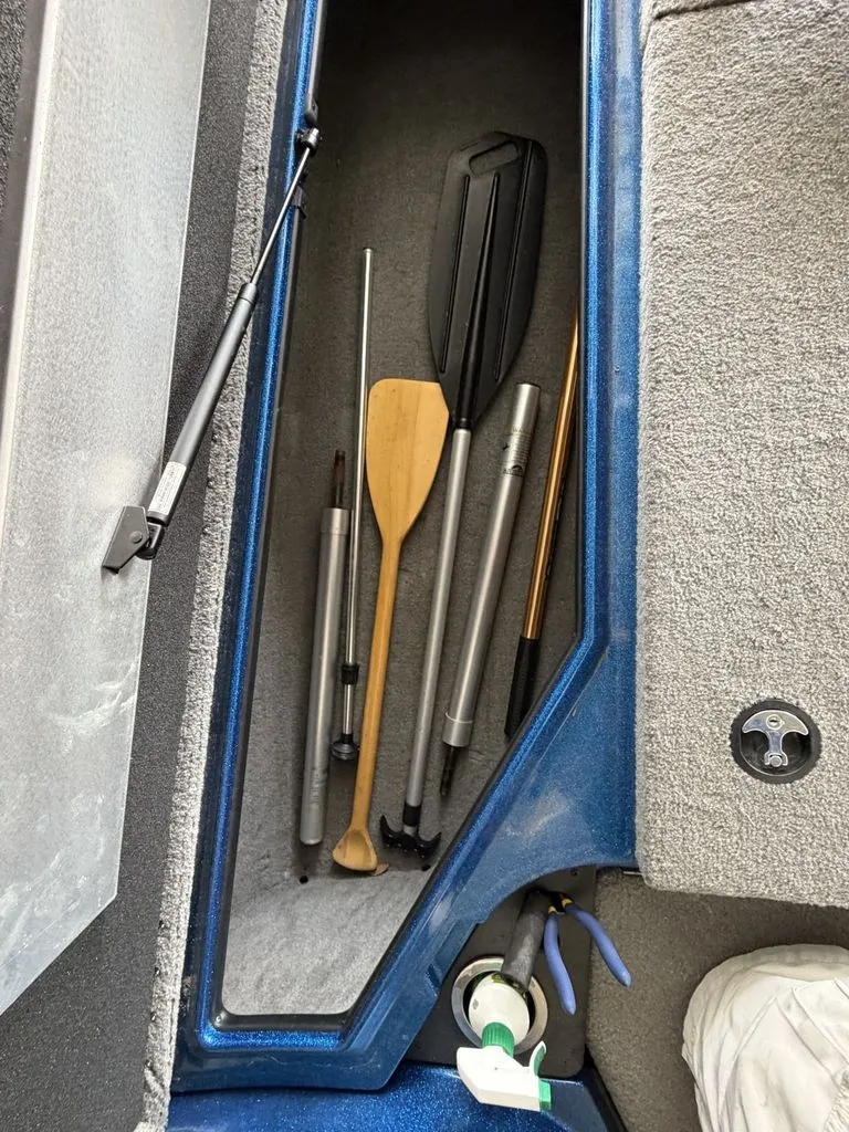 Slide: The Image of A storage compartment in a boat with paddles and poles. The floor is carpeted. - 16