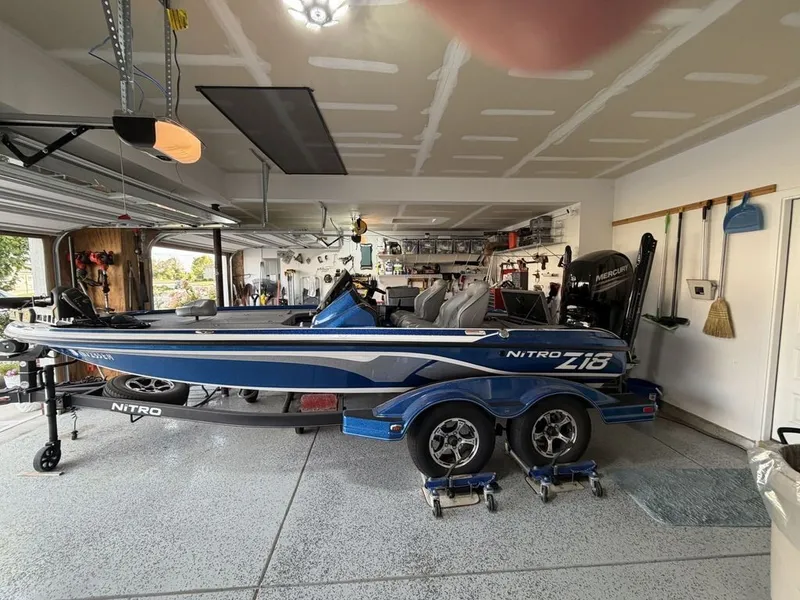 The Image of A blue 2018 Nitro Z18 boat is parked in a garage. It features a trailer and fishing gear. - 0