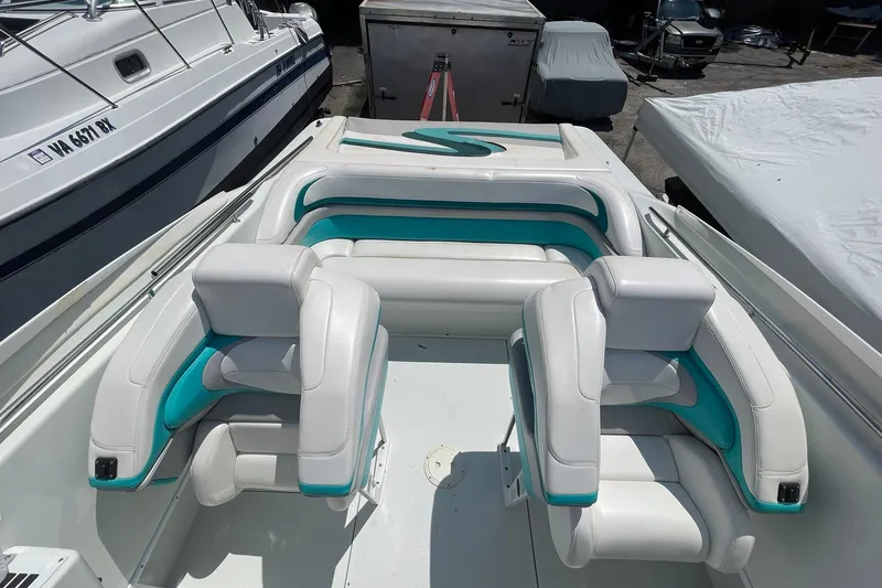 Slide: The Image of 1996 Baja 322 boat interior with white and teal seating, docked beside other boats. - 5