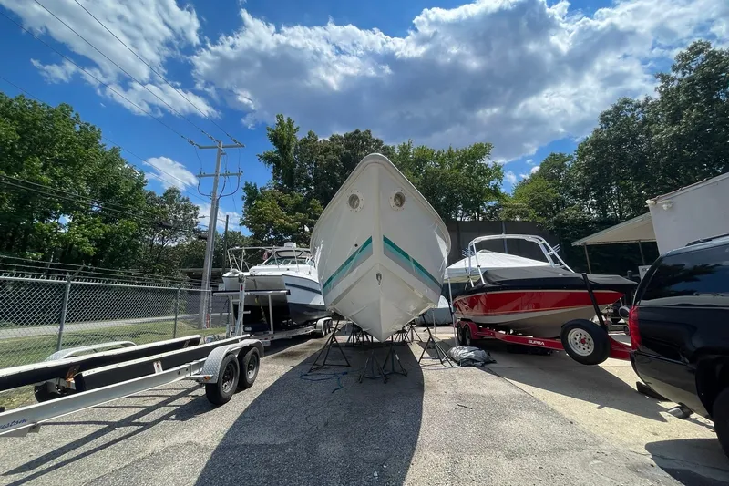 Slide: The Image of 1996 Baja 322 boat on trailer, surrounded by other boats, under a partly cloudy sky. - 16