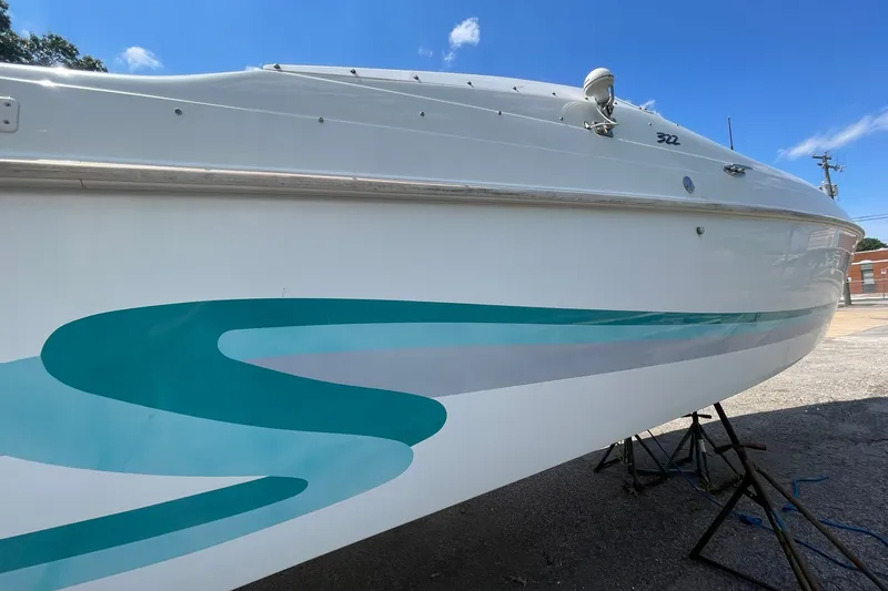Slide: The Image of 1996 Baja 322 boat with teal graphics, displayed on stands under a clear blue sky. - 14