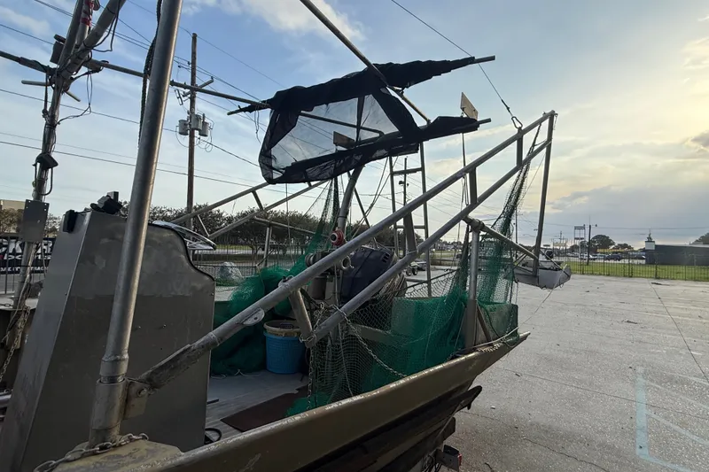 Slide: The Image of 1984 Alweld 1852PF boat with fishing nets and equipment, parked outdoors at sunset. - 8
