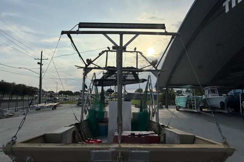 Slide: The Image of 1984 Alweld 1852PF boat with fishing equipment, parked outdoors under a cloudy sky. - 9