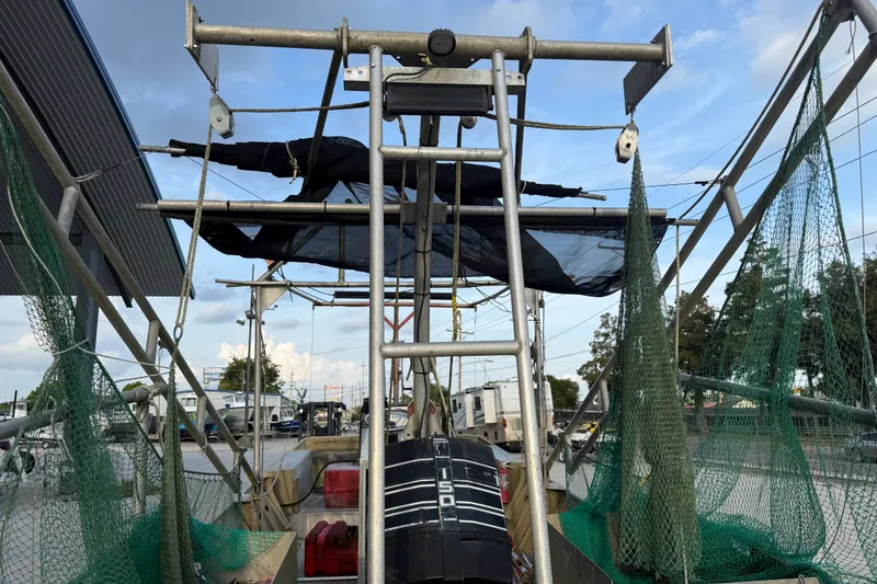 Slide: The Image of 1984 Alweld 1852PF boat with fishing nets and equipment, docked under a blue sky. - 11