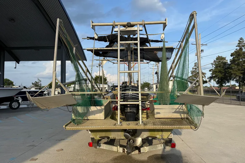 Slide: The Image of 1984 Alweld 1852PF boat with fishing nets and motor, parked outdoors. - 4