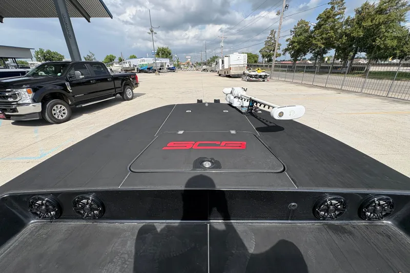 Slide: The Image of 2016 SCB 247 boat with black deck, red logo, and mounted equipment in a parking area. - 22