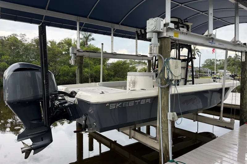 Slide: The Image of 2021 Skeeter SX2550 Fish boat on lift under canopy, dockside view. - 2