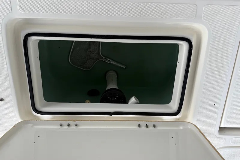 Slide: The Image of Open storage compartment on a 2021 Skeeter SX2550 Fish boat, featuring a net and equipment. - 14