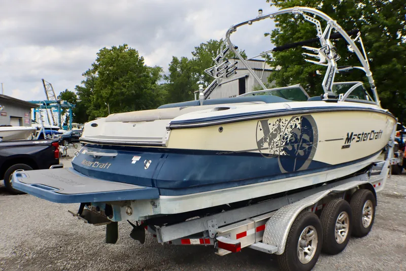 Slide: The Image of 2010 MasterCraft X-35 SS boat on a trailer, parked outdoors with trees in the background. - 7