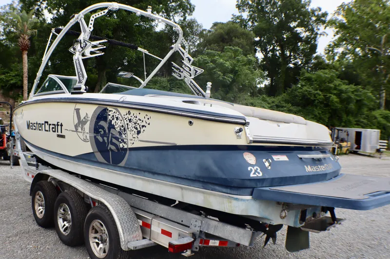 Slide: The Image of 2010 MasterCraft X-35 SS boat on trailer, parked outdoors with lush greenery background. - 5
