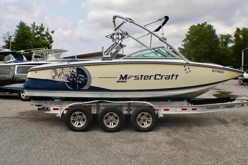 Slide: The Image of 2010 MasterCraft X-35 SS boat on trailer, parked outdoors with trees in background. - 26