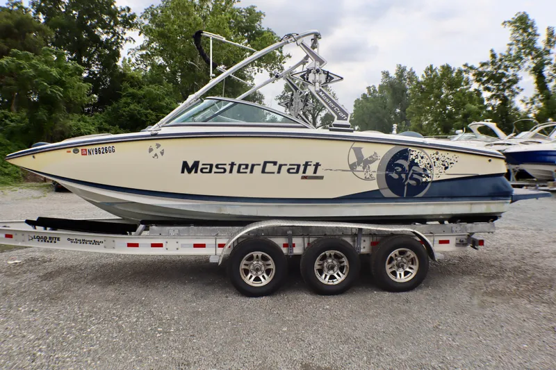 Slide: The Image of 2010 MasterCraft X-35 SS boat on trailer, parked outdoors with trees in the background. - 4