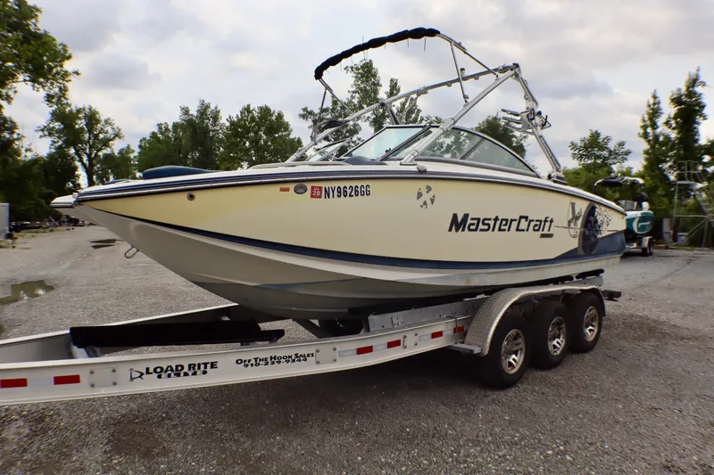 Slide: The Image of 2010 MasterCraft X-35 SS boat on trailer, parked outdoors with trees in background. - 3