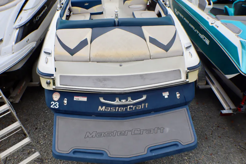 Slide: The Image of 2010 MasterCraft X-35 SS boat, rear view, featuring cushioned seating and branded swim platform. - 25