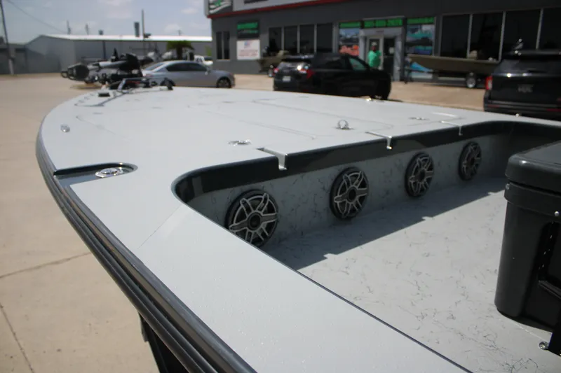 Slide: The Image of 2025 Mamba 24VX boat deck with speakers, parked outdoors near a showroom. - 6